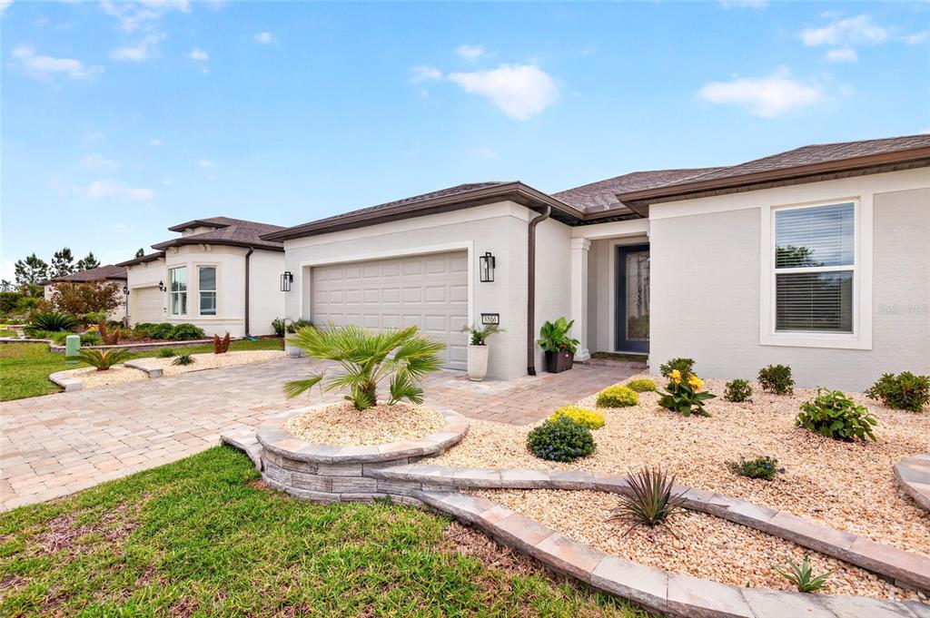 A single-story house exterior features a paved driveway, a two-car garage, and landscaped rock beds — 8866 SW 57TH PLACE ROAD, OCALA, FL