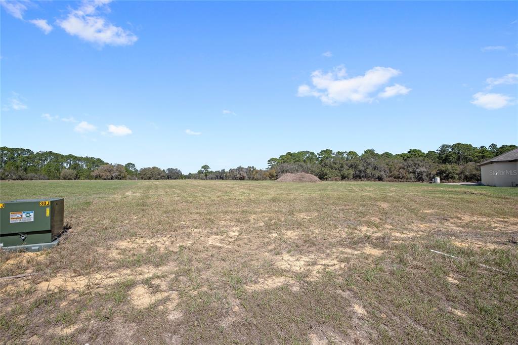 A large, flat, grassy vacant lot under a bright blue sky with scattered clouds — 38361 LAKE MEADOW COURT, UMATILLA, FL
