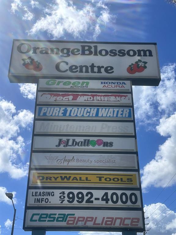 A tall, multi-tenant sign for the Orange Blossom Centre stands against a blue sky — 2585 ORANGE BLOSSOM, KISSIMMEE, FL