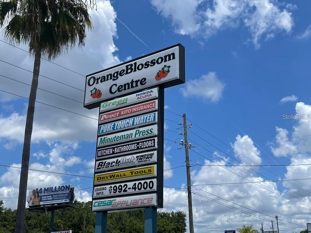 A tall, multi-tenant commercial sign stands outdoors under a blue sky with clouds — 2585 ORANGE BLOSSOM, KISSIMMEE, FL