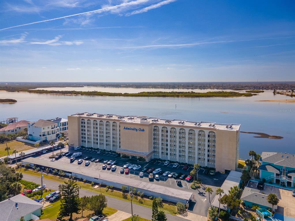 An aerial view shows the Admiralty Club apartment building situated along a waterfront — 3606 S PENINSULA DRIVE UNIT 809, PORT ORANGE, FL