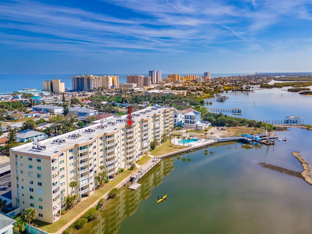An aerial view shows a multi-story waterfront condominium building with a red arrow pointing upward — 3606 S PENINSULA DRIVE UNIT 809, PORT ORANGE, FL
