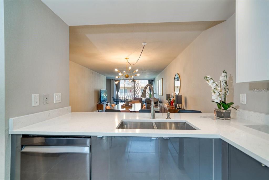 A kitchen sink and counter overlook an open-concept dining and living area — 105 ISLAND WAY UNIT 132, CLEARWATER, FL