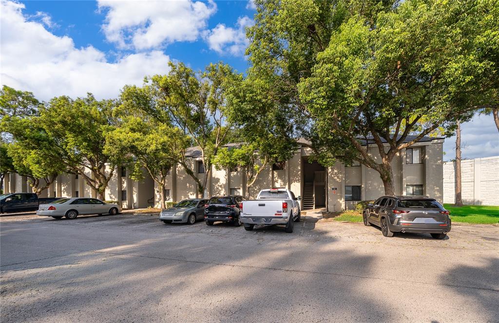 A two-story apartment building exterior with a parking lot and several parked cars — 163 SPRINGWOOD CIRCLE UNIT B, LONGWOOD, FL