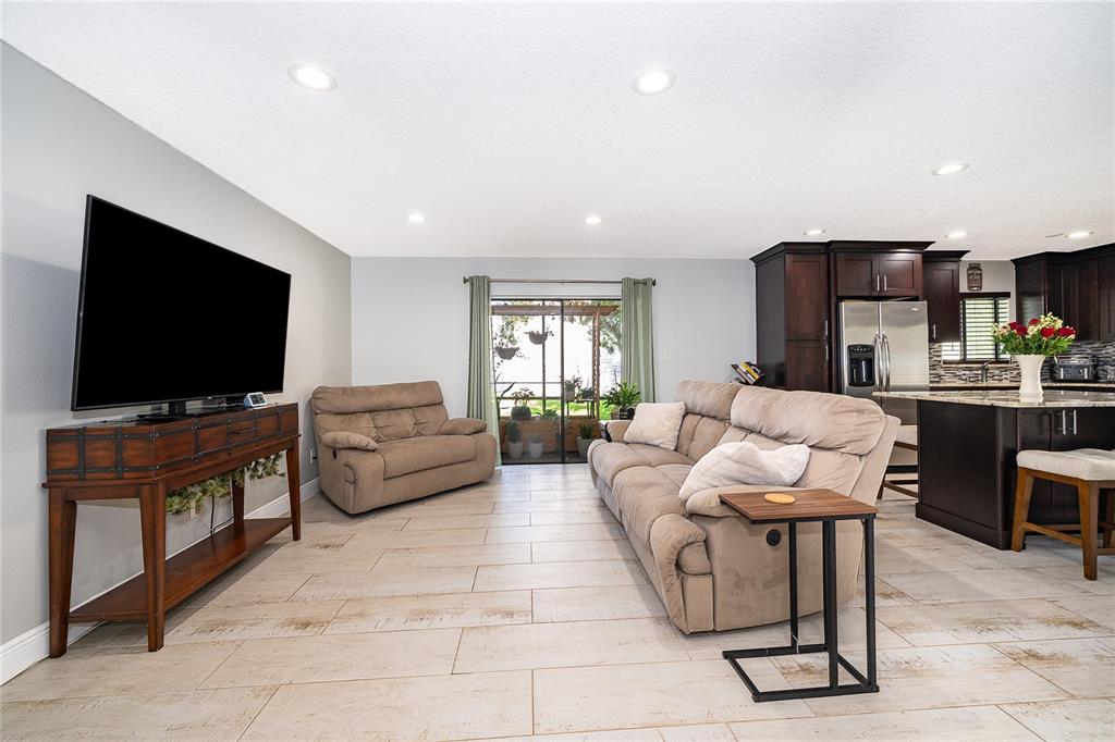 A living room with tile floors, a television on a console, and a beige sofa — 163 SPRINGWOOD CIRCLE UNIT B, LONGWOOD, FL