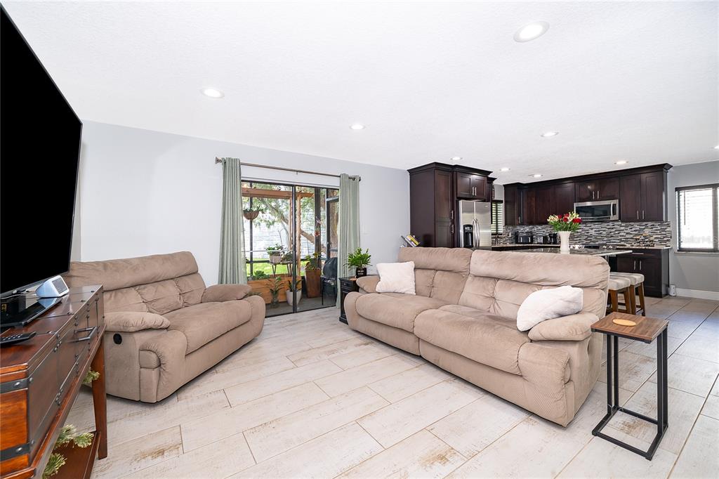 A living room with light tile floors, two tan sofas, and an open-concept kitchen — 163 SPRINGWOOD CIRCLE UNIT B, LONGWOOD, FL