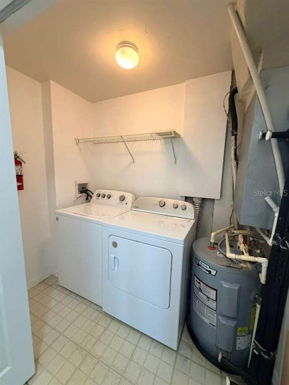 A laundry room features a white washer and dryer next to a water heater — 6413 ASTOR VILLAGE AVENUE UNIT 303, ORLANDO, FL