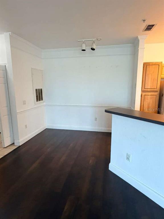 An empty dining area features dark wood flooring, white wainscoting, and a track lighting fixture — 6413 ASTOR VILLAGE AVENUE UNIT 303, ORLANDO, FL