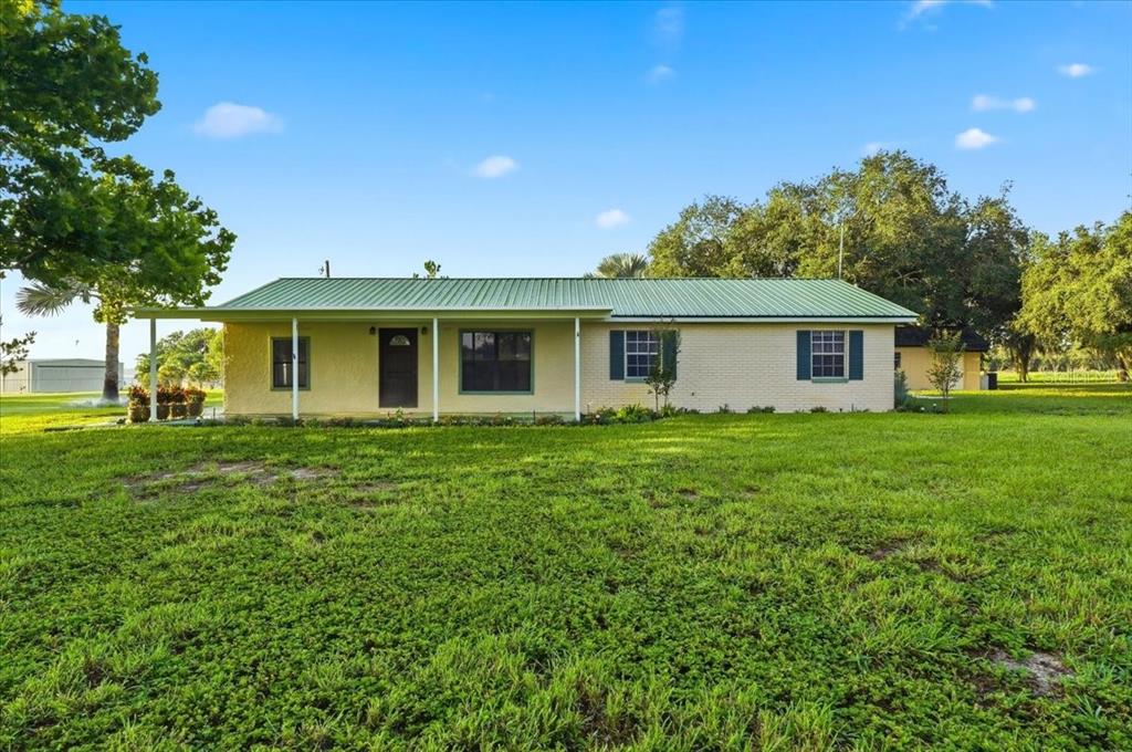 A single-story house with a green metal roof and light-colored brick exterior — 1645 HWY 630 W, FROSTPROOF, FL