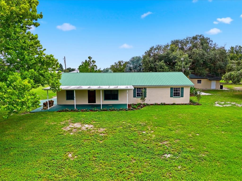 A single-story house with a green metal roof and a front porch sits on grass — 1645 HWY 630 W, FROSTPROOF, FL