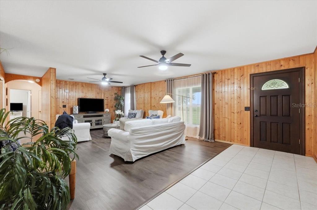 A living room features wood-paneled walls, a white sofa, and a tiled entryway — 1645 HWY 630 W, FROSTPROOF, FL