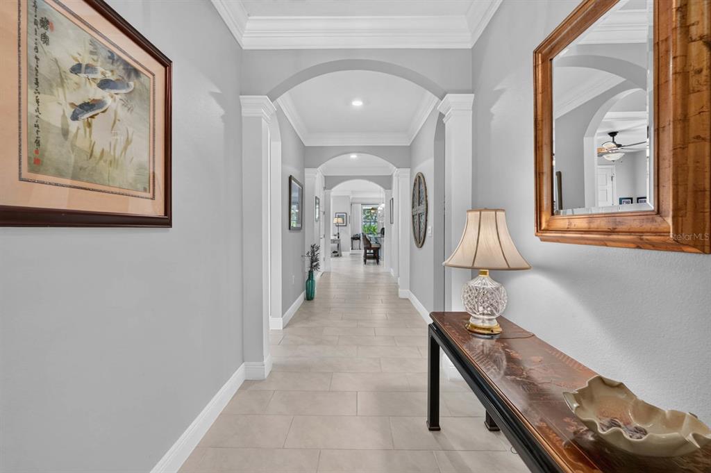 A long, light-gray hallway features arched doorways, tile flooring, and a console table with decor — 2881 MONAGHAN DRIVE, ORMOND BEACH, FL