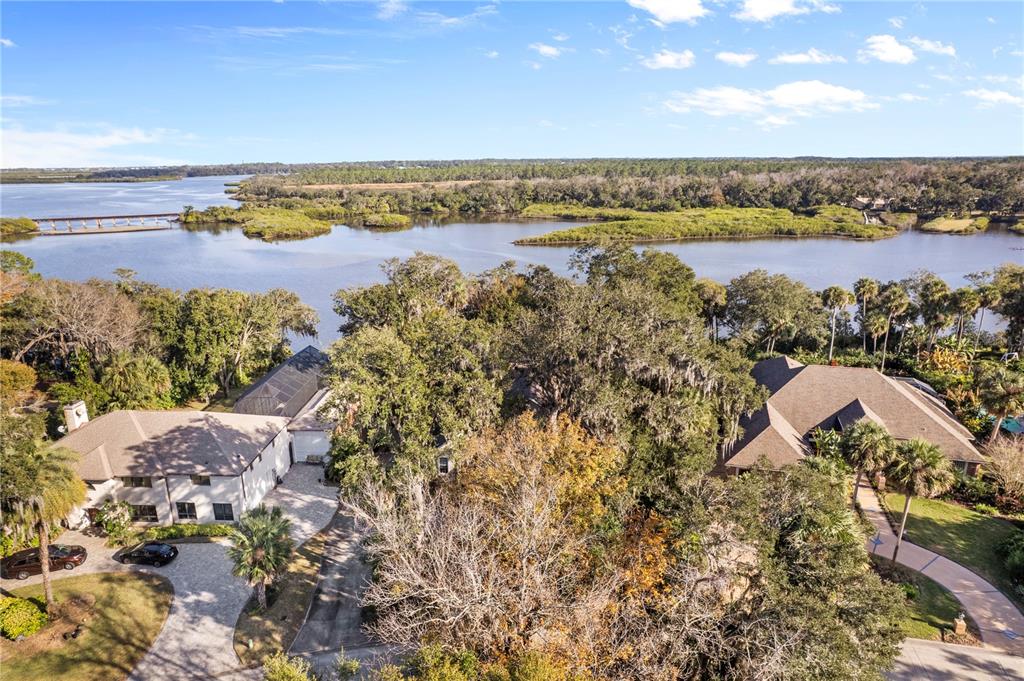 An aerial view shows two houses surrounded by trees near a large body of water — 6311 PALMAS BAY CIRCLE, PORT ORANGE, FL