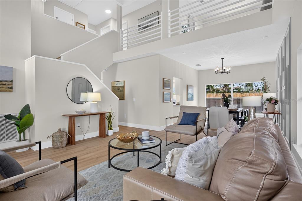 A living room features a high ceiling, a staircase, and a leather sofa — 11328 CLAYRIDGE DRIVE, TAMPA, FL