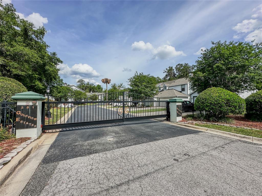 A black metal gate marks the entrance to a residential community with landscaped grounds — 231 NE 28TH AVENUE UNIT 308, OCALA, FL