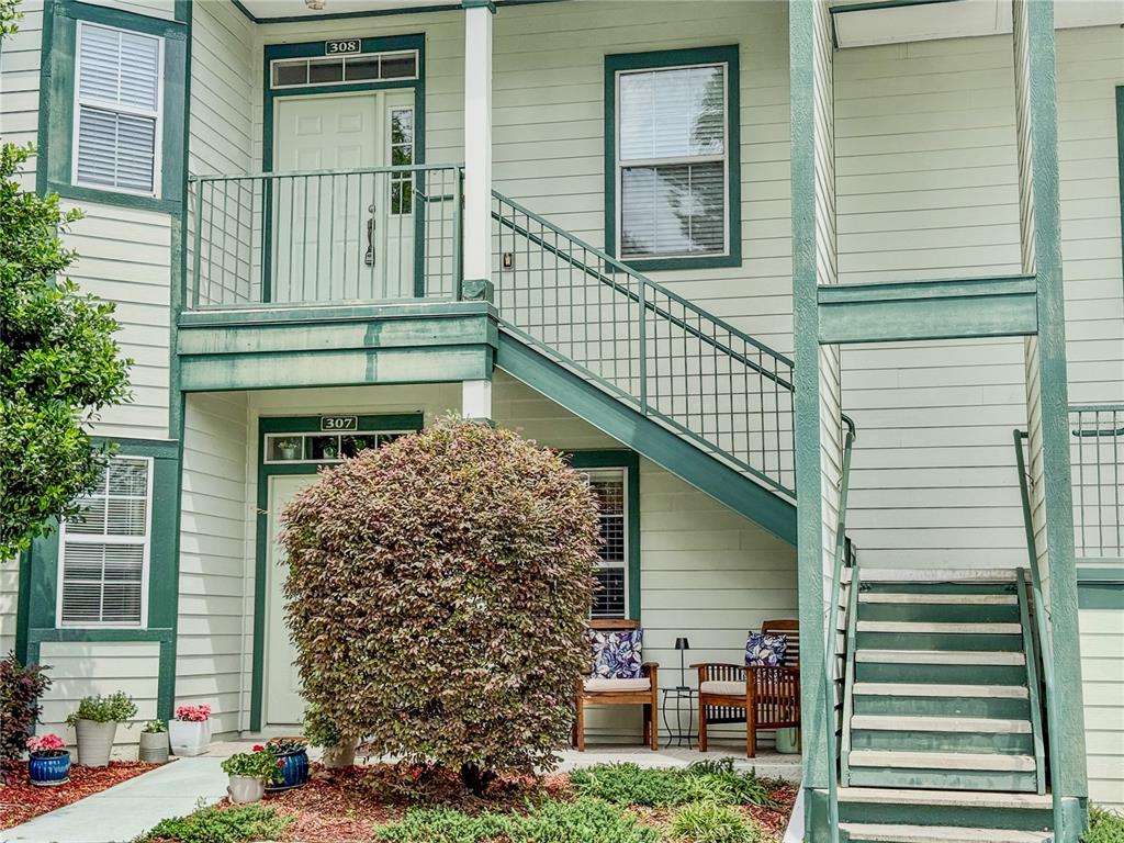 Exterior view of a two-story apartment building with green trim, stairs, and a small patio — 231 NE 28TH AVENUE UNIT 308, OCALA, FL