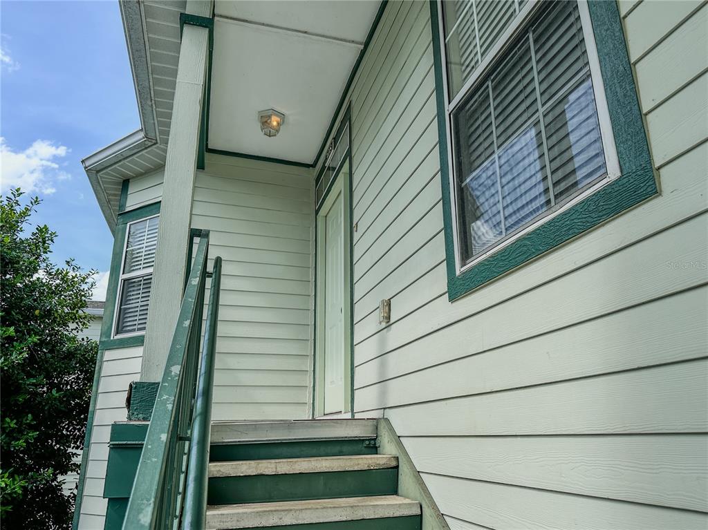 Exterior view of a staircase leading to a light green house entrance with siding — 231 NE 28TH AVENUE UNIT 308, OCALA, FL