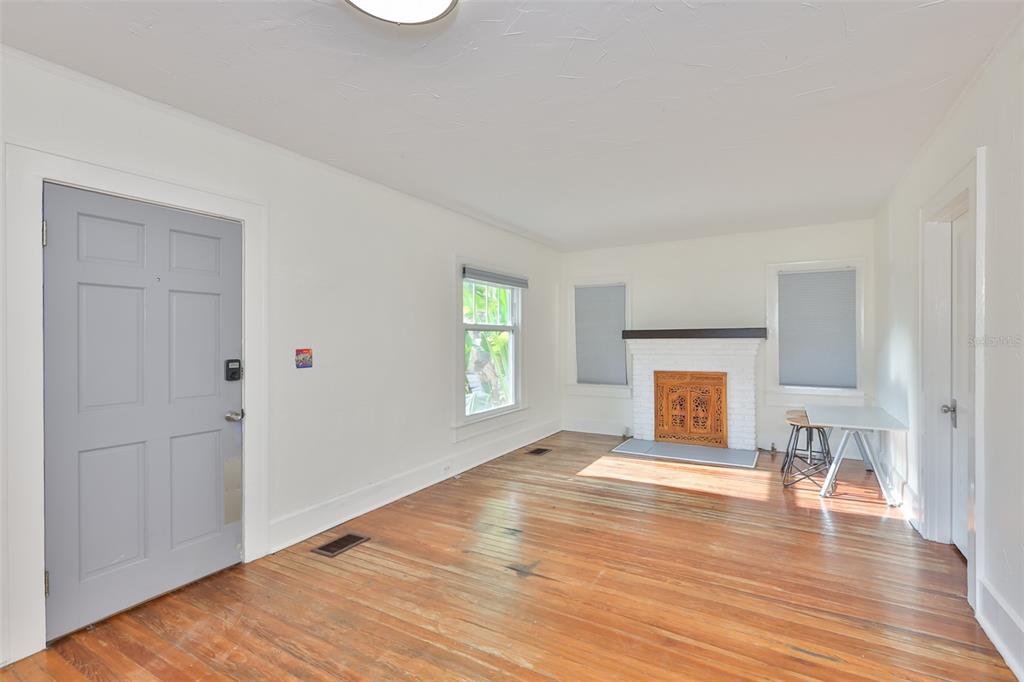 A living room features hardwood floors, a white brick fireplace, and a gray entry door — 340 MOFFETT COURT N, ST PETERSBURG, FL