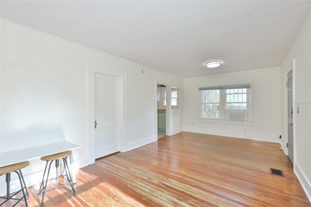 A bright, empty room features hardwood floors, white walls, a window, and a doorway — 340 MOFFETT COURT N, ST PETERSBURG, FL