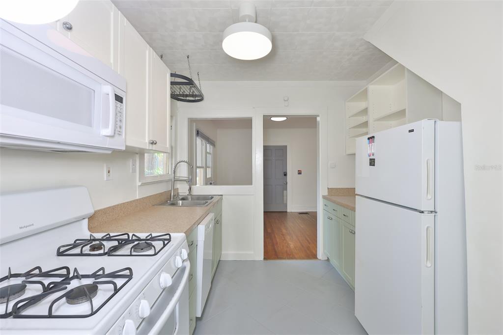 A kitchen features white cabinets, a gas range, a white refrigerator, and light green lower cabinets — 340 MOFFETT COURT N, ST PETERSBURG, FL