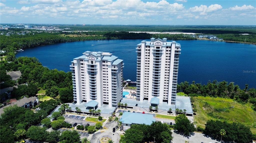 An aerial view shows two tall residential towers situated on the shore of a lake — 13415 BLUE HERON BEACH DRIVE UNIT 109, ORLANDO, FL