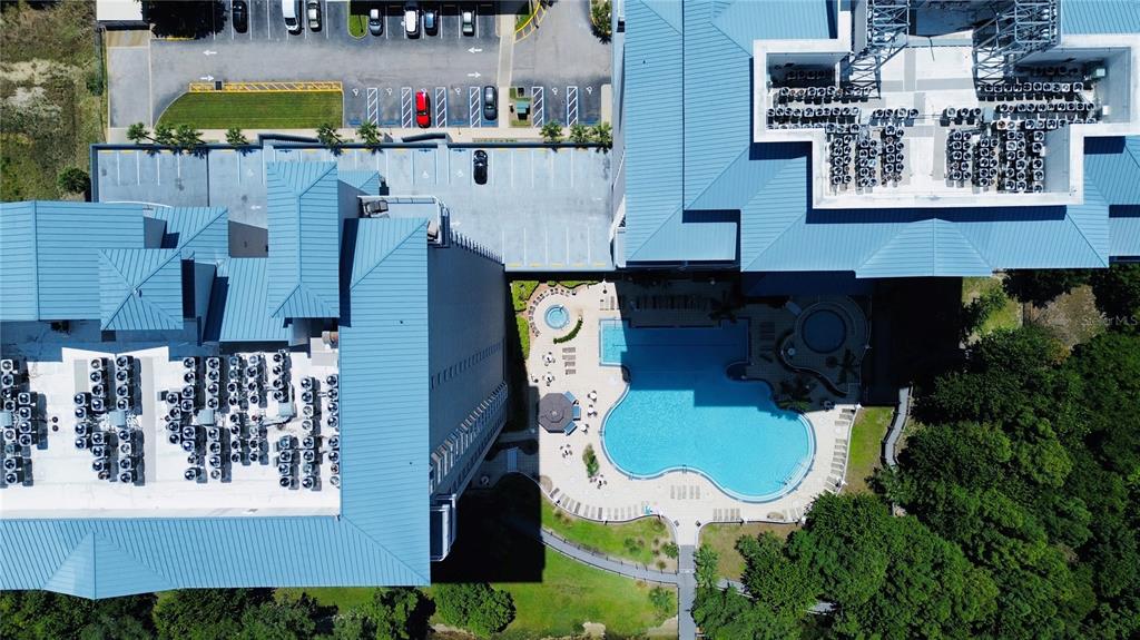 An aerial view shows a large building with a blue metal roof, pool, and parking — 13415 BLUE HERON BEACH DRIVE UNIT 109, ORLANDO, FL