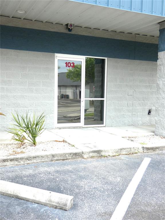 The exterior of a commercial building features a glass door labeled 103 and concrete walls — 1882 PORTER LAKE DRIVE UNIT 103, SARASOTA, FL