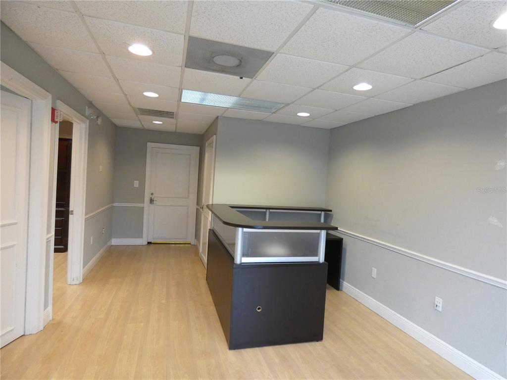 An office reception area features a dark desk, light wood flooring, and gray walls — 1882 PORTER LAKE DRIVE UNIT 103, SARASOTA, FL