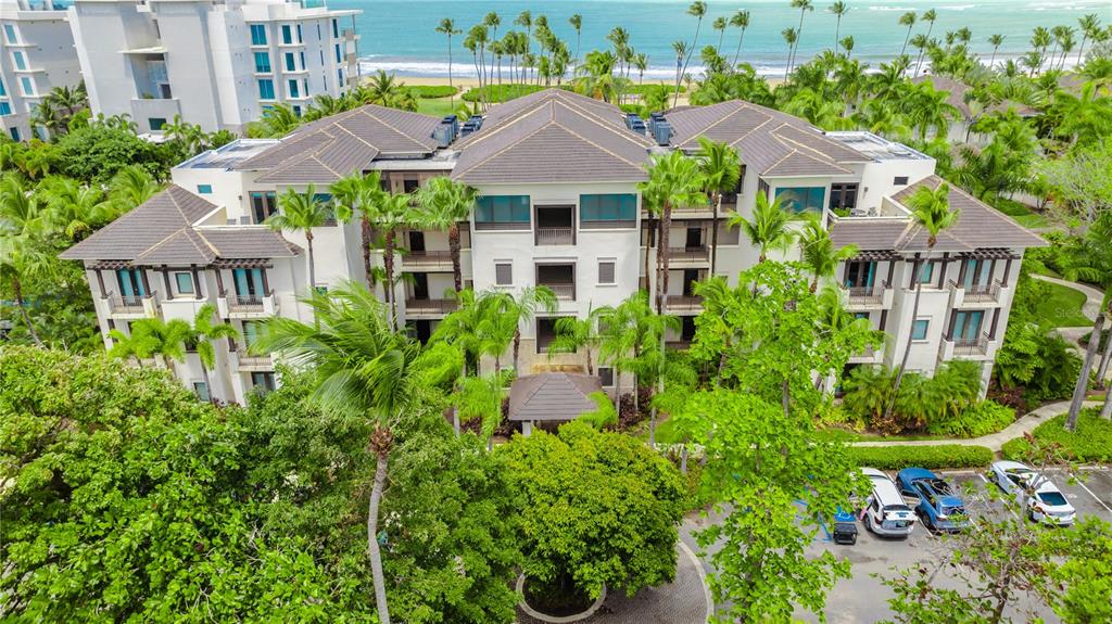 An aerial view shows a multi-story resort building surrounded by palm trees near the ocean — Bahia Beach Golf Club LAS VENTANAS II CONDOMINIUM UNIT 209, RIO GRANDE, PR