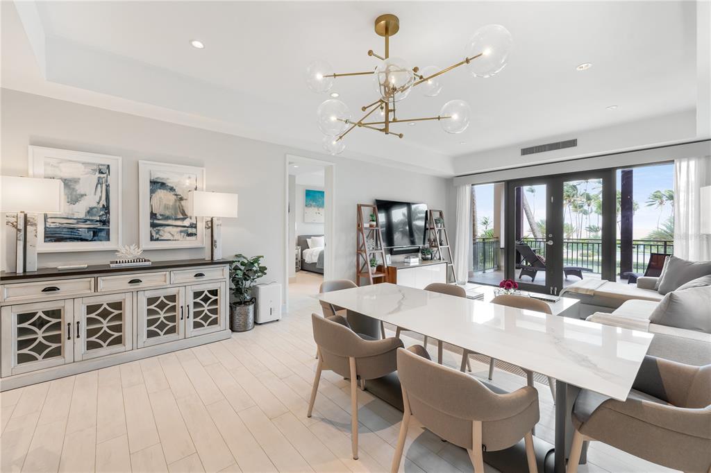 A bright dining and living area features a modern chandelier, white marble table, and balcony — Bahia Beach Golf Club LAS VENTANAS II CONDOMINIUM UNIT 209, RIO GRANDE, PR