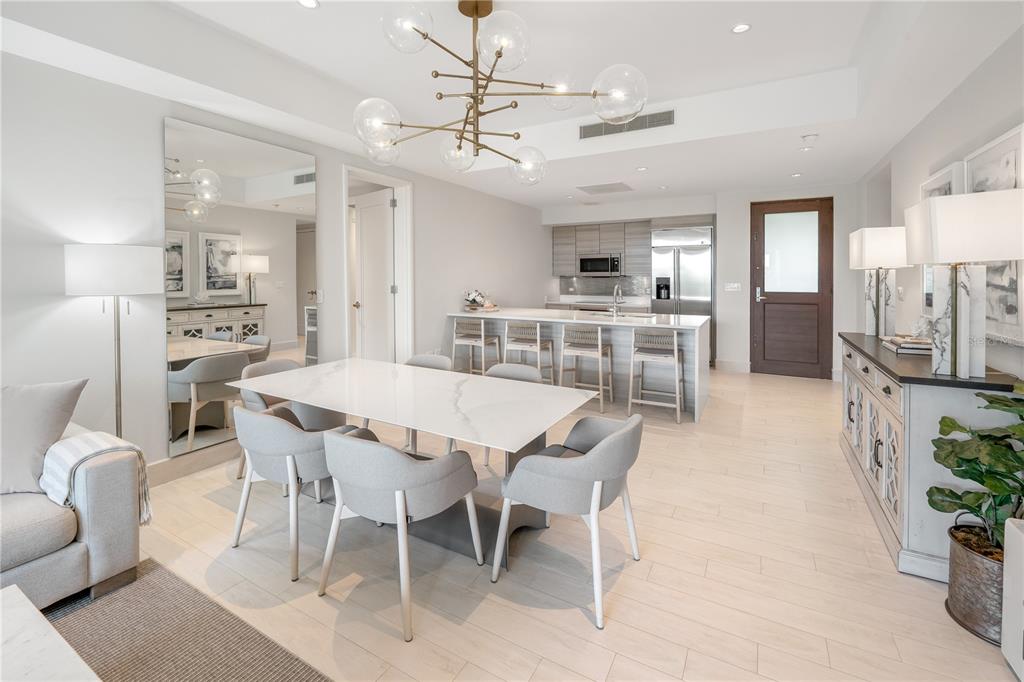 A modern dining area features a white marble table, gray chairs, and a kitchen island — Bahia Beach Golf Club LAS VENTANAS II CONDOMINIUM UNIT 209, RIO GRANDE, PR