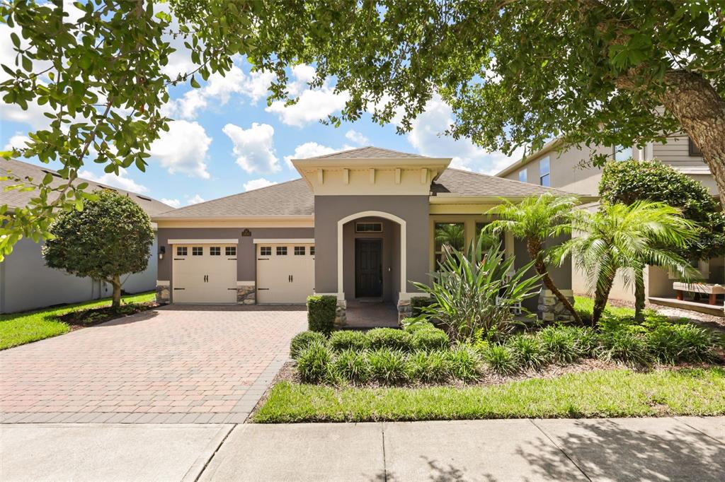 A single-story house with a two-car garage, brick paver driveway, and landscaped front yard — 16082 HAMPTON CROSSING DRIVE, WINTER GARDEN, FL