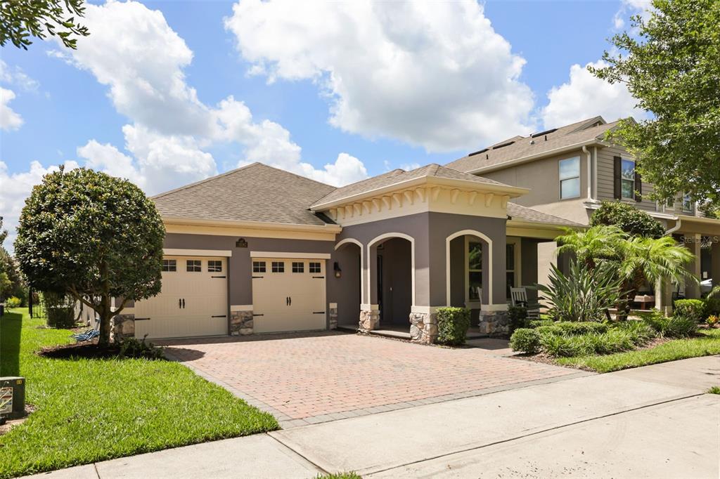 A single-story house with a two-car garage, stone accents, and a brick paver driveway — 16082 HAMPTON CROSSING DRIVE, WINTER GARDEN, FL