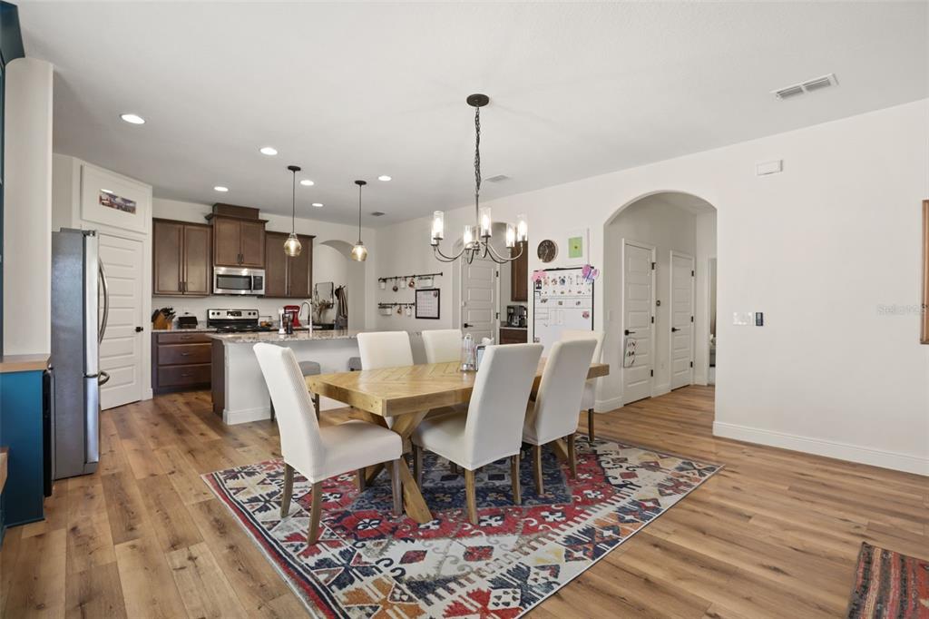 A dining room with a wooden table, patterned rug, and built-in blue bar cabinetry — 16082 HAMPTON CROSSING DRIVE, WINTER GARDEN, FL