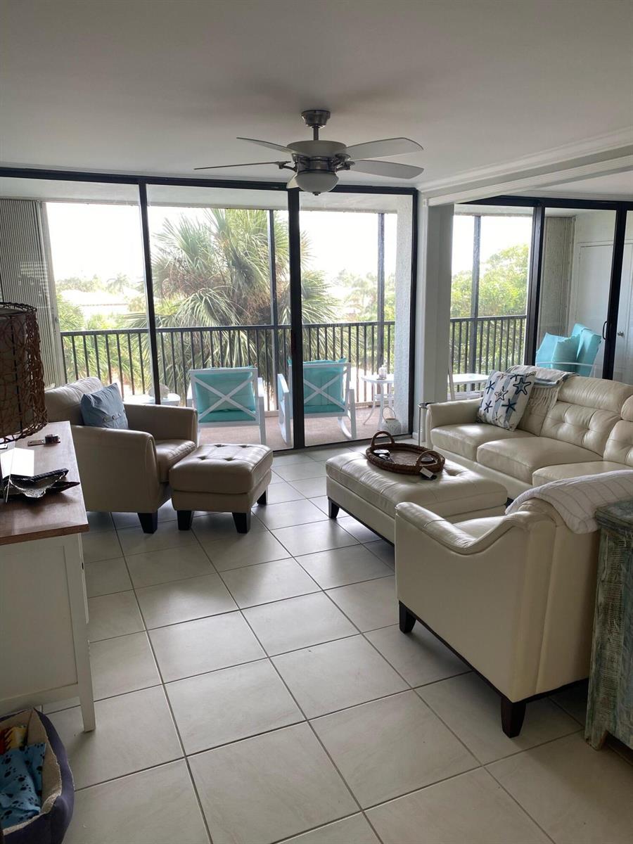 A living room with tile floors, leather furniture, and sliding glass doors leading to a balcony — 1605 S Us Highway 1, Jupiter FL 33477, JUPITER, FL