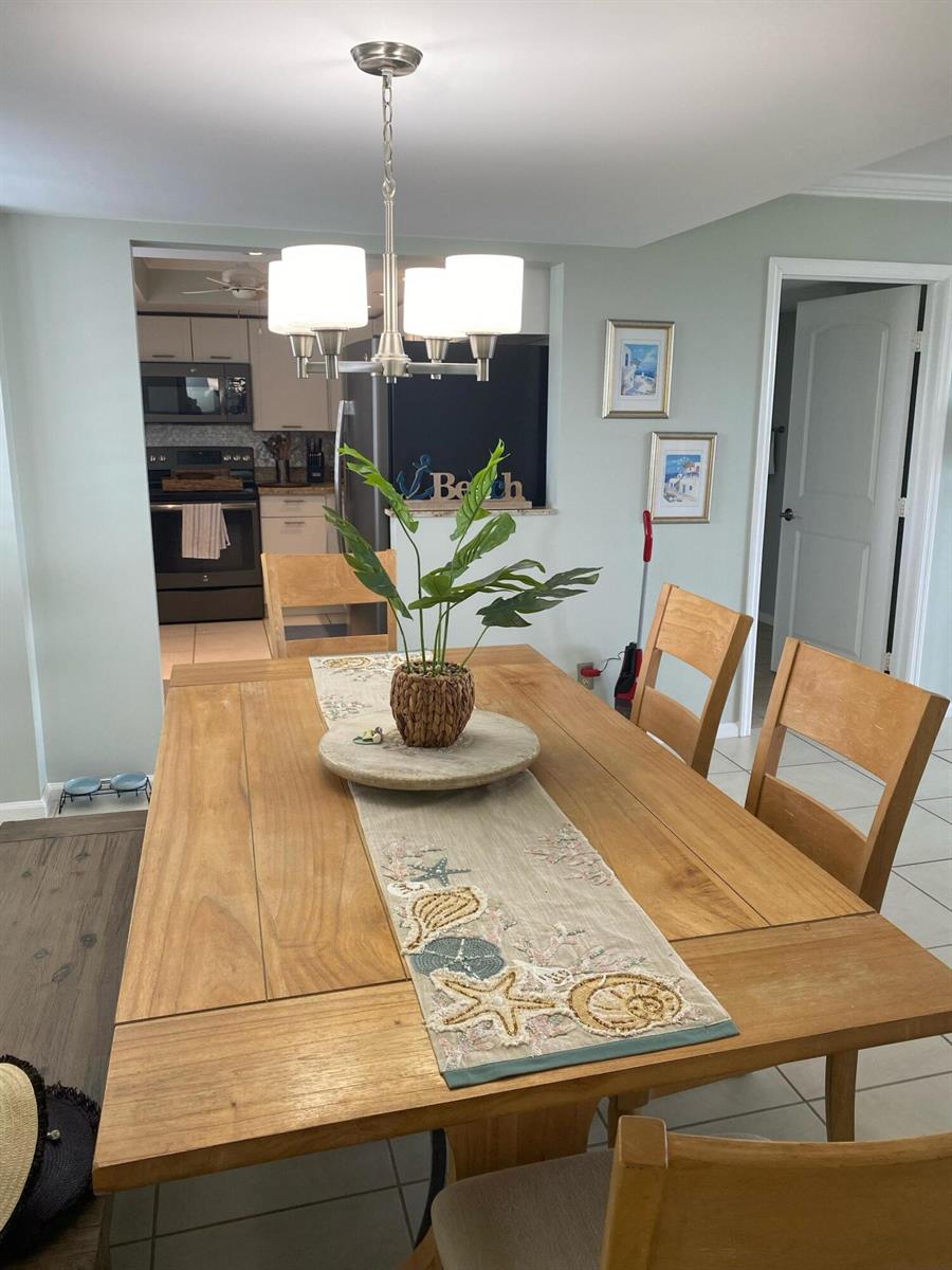 A dining room features a wooden table with a coastal runner and a light fixture — 1605 S Us Highway 1, Jupiter FL 33477, JUPITER, FL