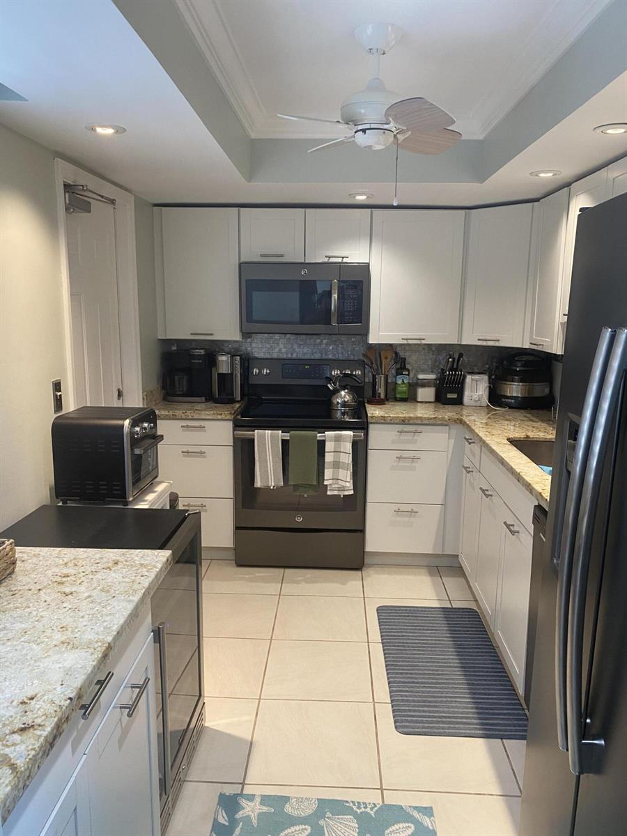 A kitchen features white cabinets, granite countertops, stainless steel appliances, and light-colored tile flooring — 1605 S Us Highway 1, Jupiter FL 33477, JUPITER, FL