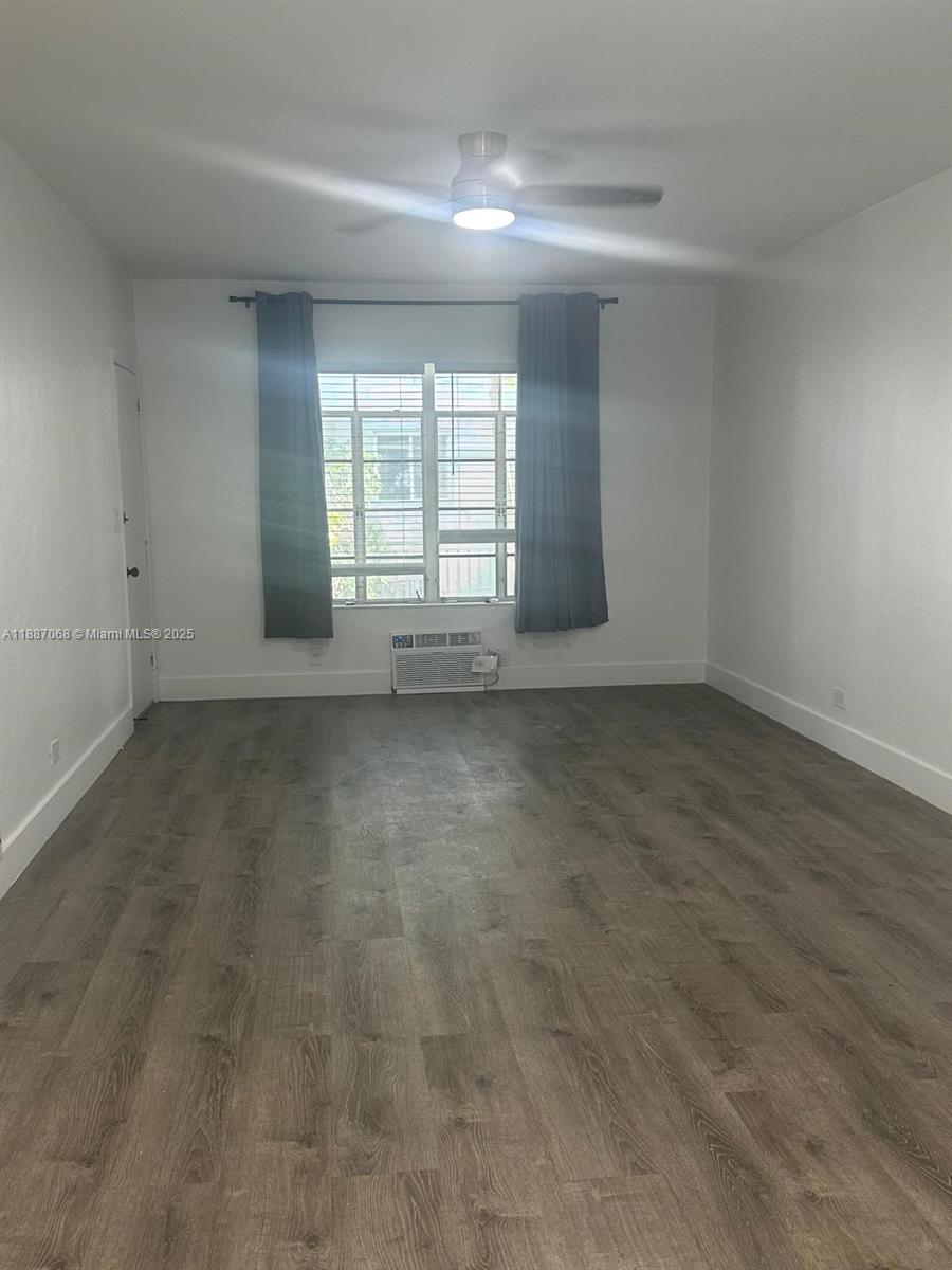An empty room features gray wood-look flooring, white walls, a ceiling fan, and a window — 6805 Abbott Ave # 1, Miami Beach FL 33141, MIAMI BEACH, FL