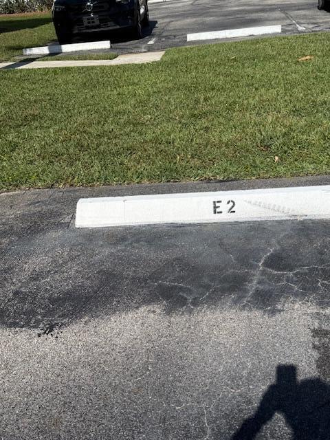 A parking space marked E2 with a concrete wheel stop in an asphalt lot — 1219 S Lakes End Drive # 2, Fort Pierce FL 34982, FORT PIERCE, FL