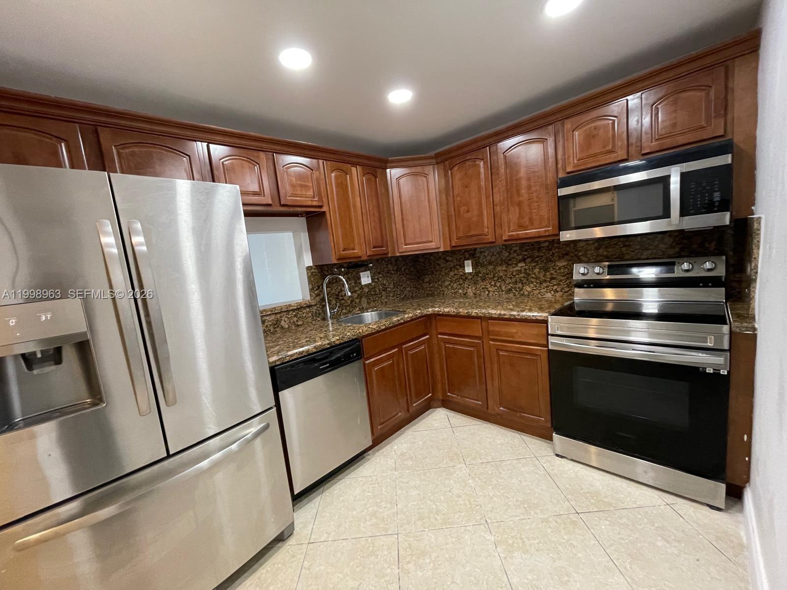 A kitchen features stainless steel appliances, dark wood cabinets, and granite countertops — 9143 SW 77th Ave # B105, Miami FL 33156, MIAMI, FL