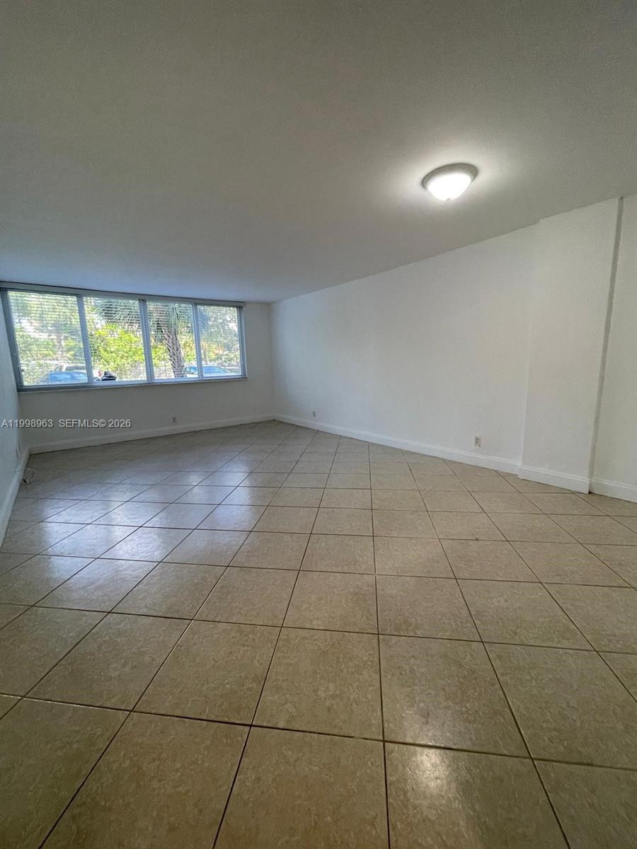 An empty room features white walls, a tiled floor, and a large window — 9143 SW 77th Ave # B105, Miami FL 33156, MIAMI, FL