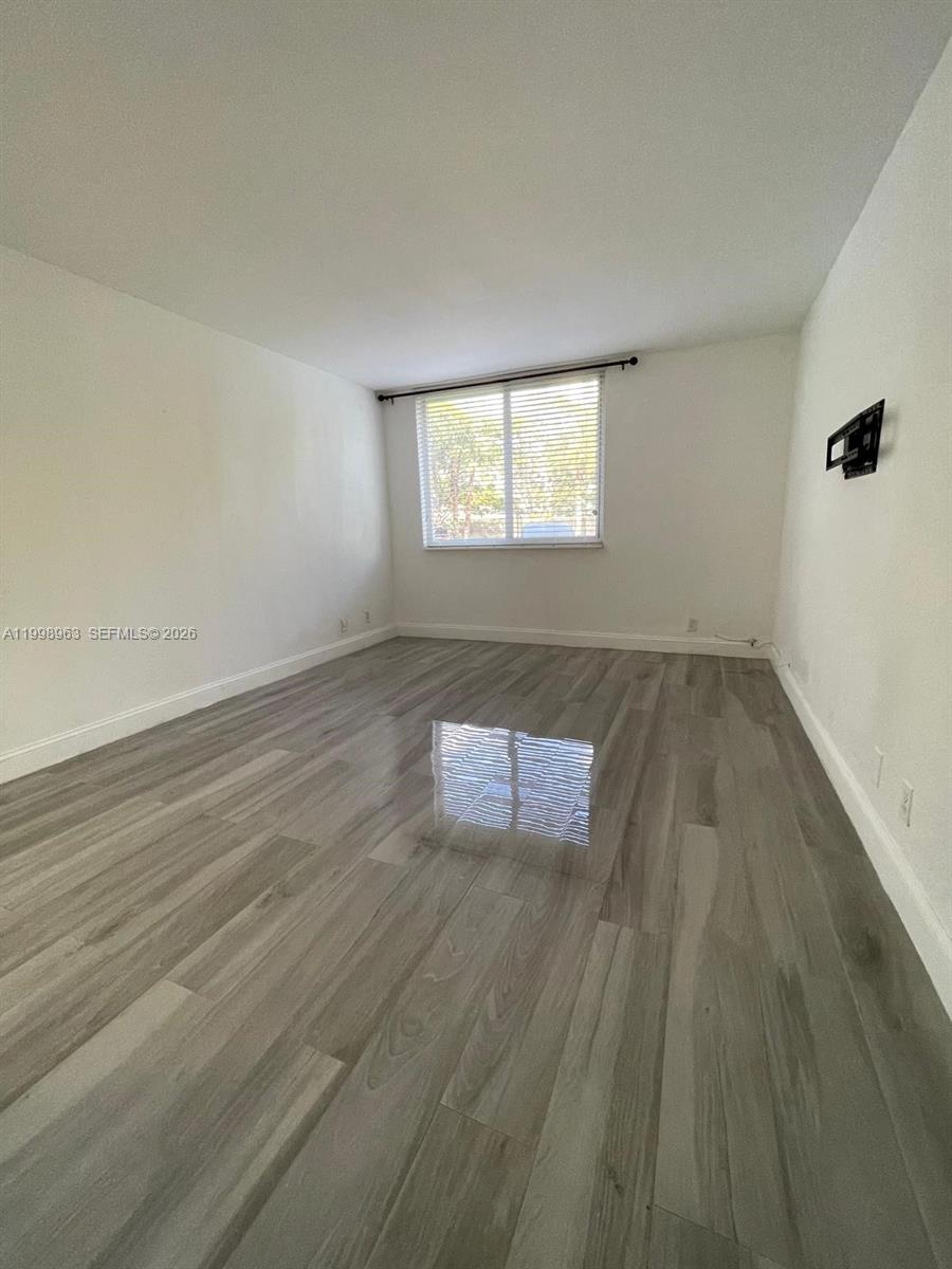 An empty room features white walls, a single window with blinds, and gray wood-look flooring — 9143 SW 77th Ave # B105, Miami FL 33156, MIAMI, FL