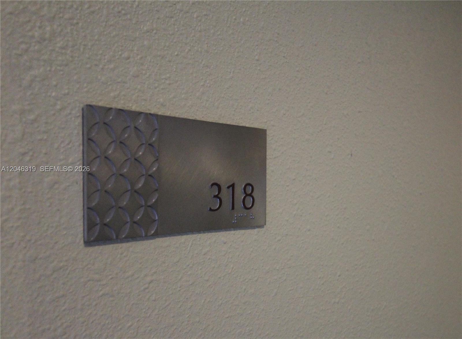 A metal sign with the number 318 and braille is mounted on a textured wall — 10275 Collins Ave # 318, Bal Harbour FL 33154, BAL HARBOUR, FL