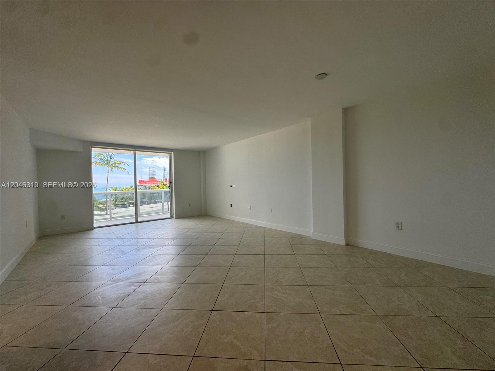An empty room features beige tile flooring, white walls, and a sliding glass door to a balcony — 10275 Collins Ave # 318, Bal Harbour FL 33154, BAL HARBOUR, FL