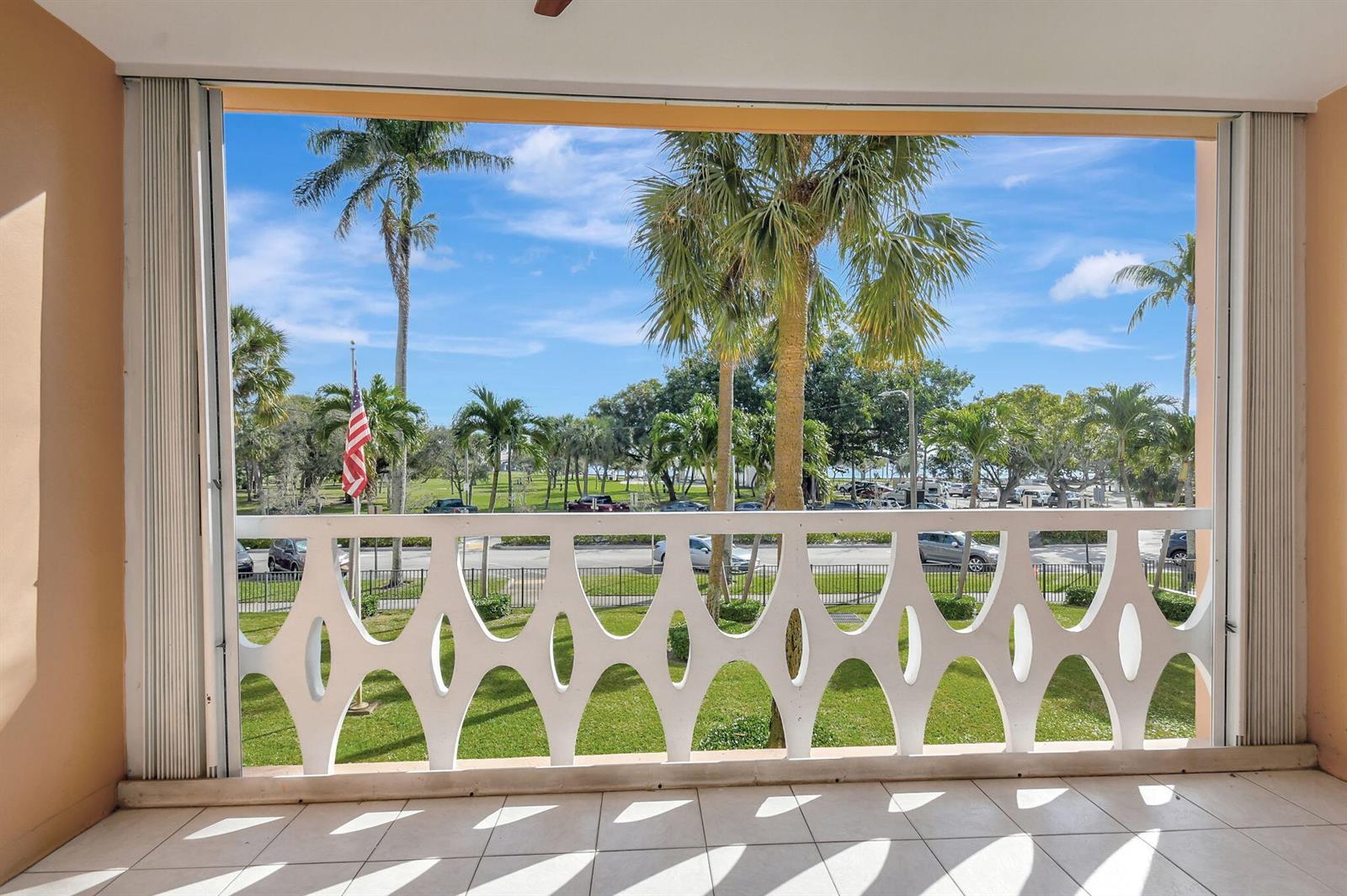 A balcony with a white decorative railing overlooks a palm-lined street and a park — 15 S Golfview Road # 204, FL 33460, FL