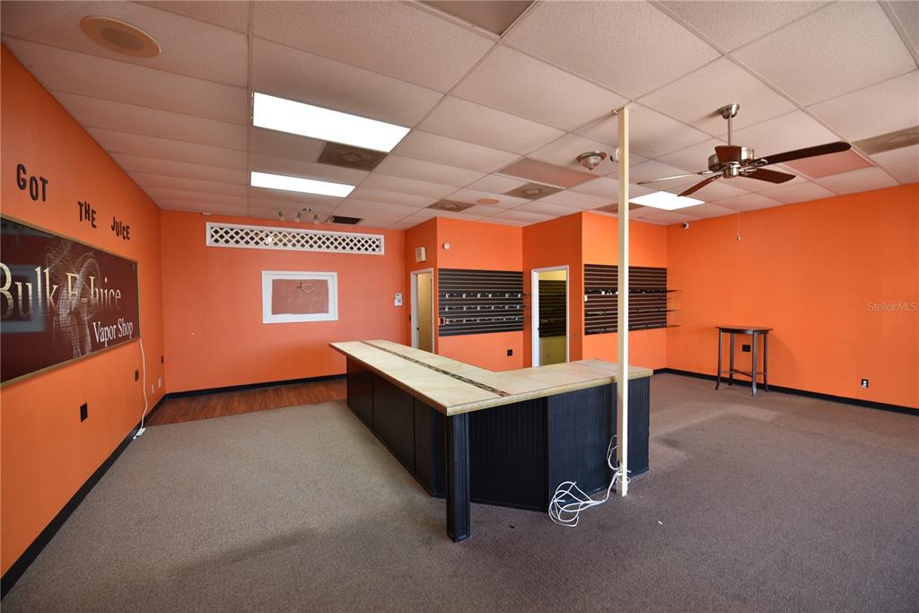 An empty commercial space features orange walls, a central service counter, and a drop ceiling — 5126 US HIGHWAY 19, NEW PORT RICHEY, FL