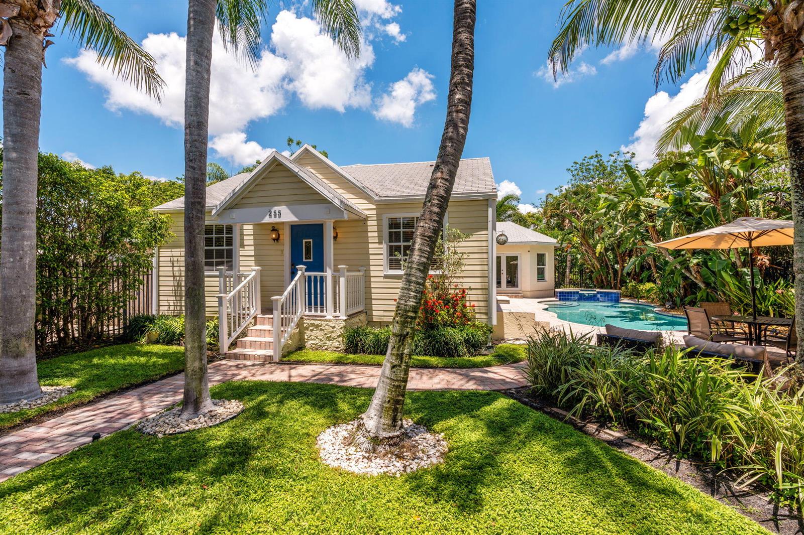A yellow house with a blue front door, a swimming pool, and palm trees — 255 NE 12th Street, Delray Beach FL 33444, DELRAY BEACH, FL