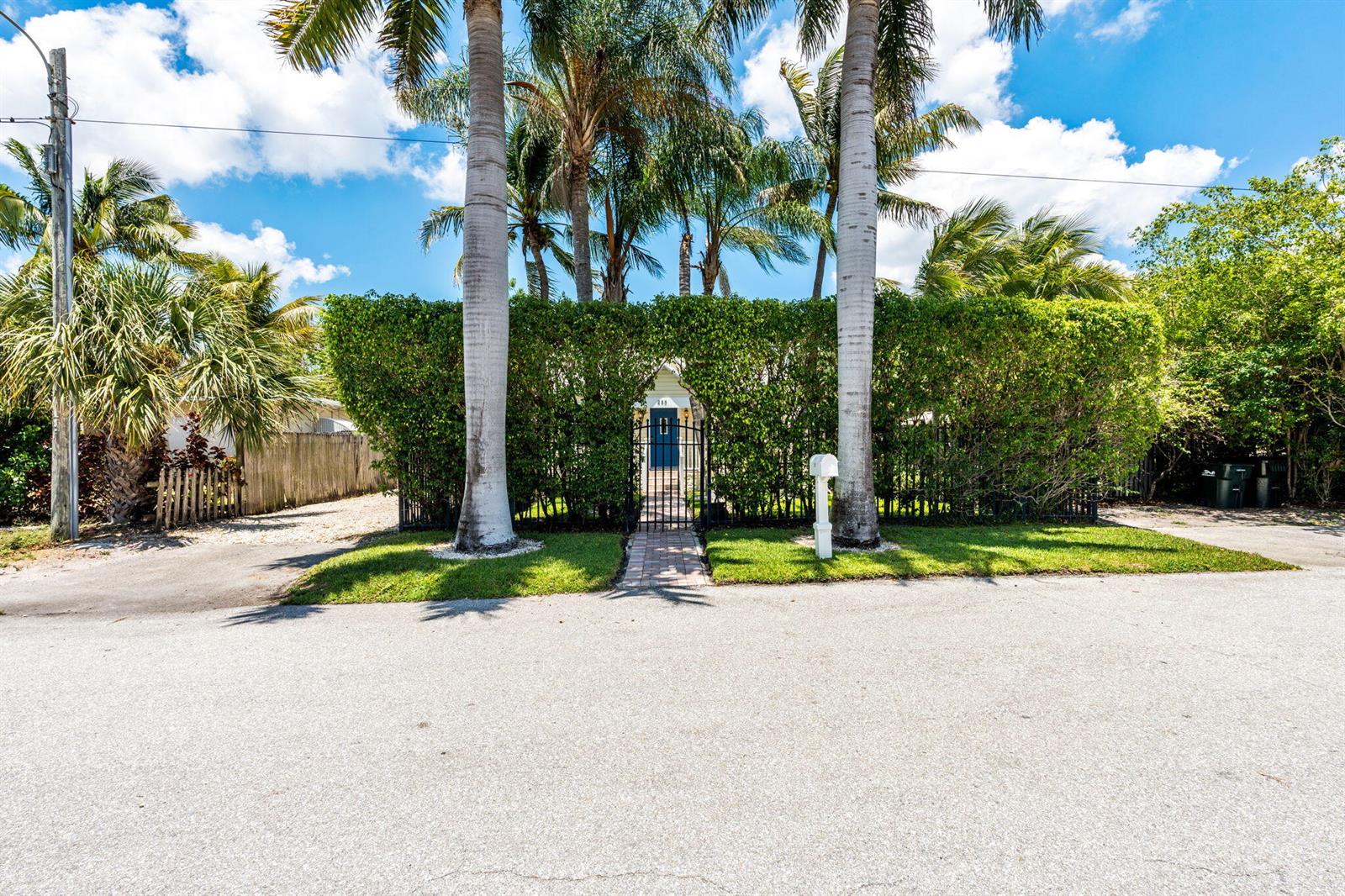 A blue front door is visible behind a tall hedge and iron gate — 255 NE 12th Street, Delray Beach FL 33444, DELRAY BEACH, FL