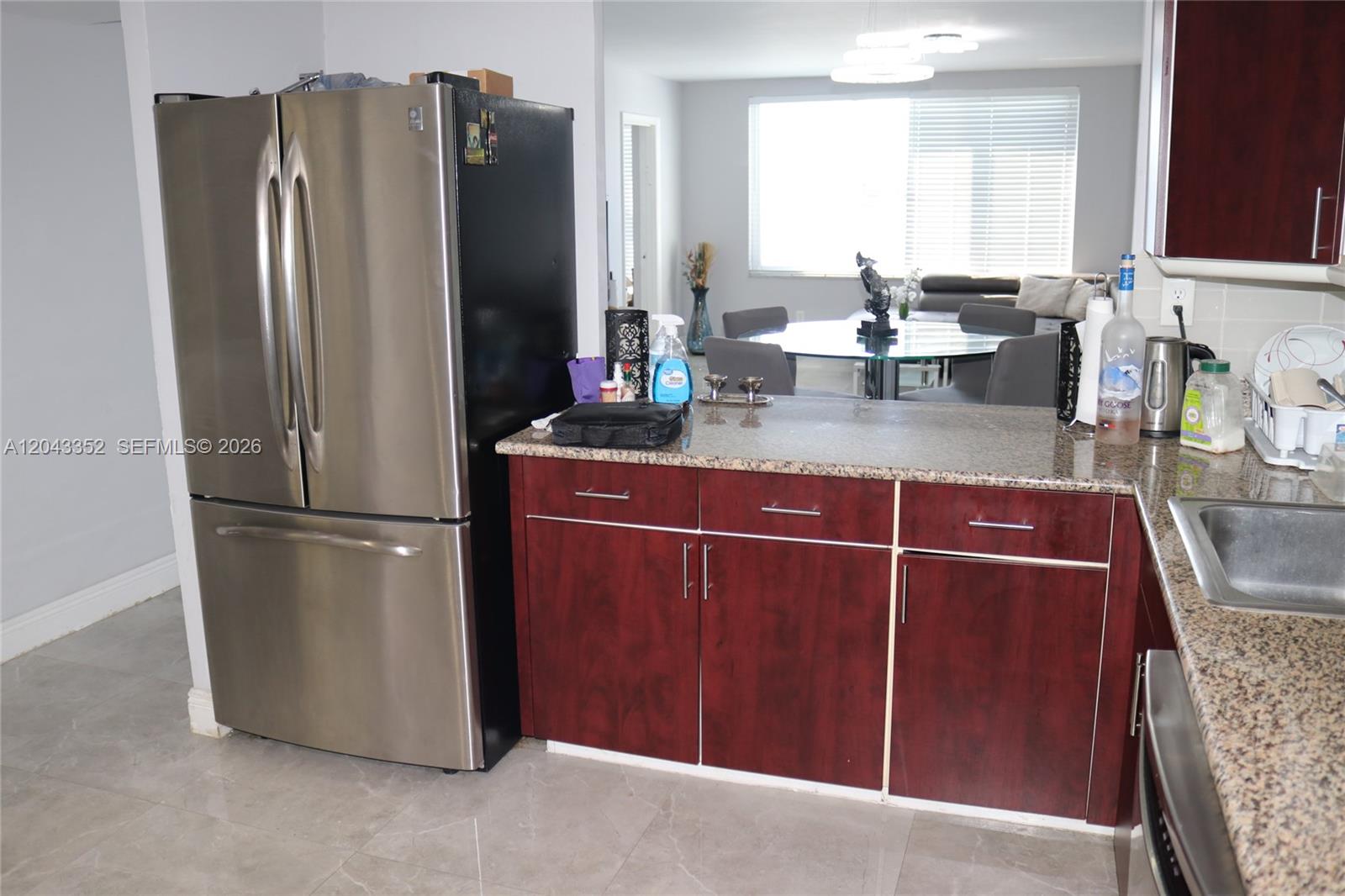 A kitchen features stainless steel appliances, dark wood cabinets, and granite countertops — 1150 NE 191st St # 37, Miami FL 33179, MIAMI, FL