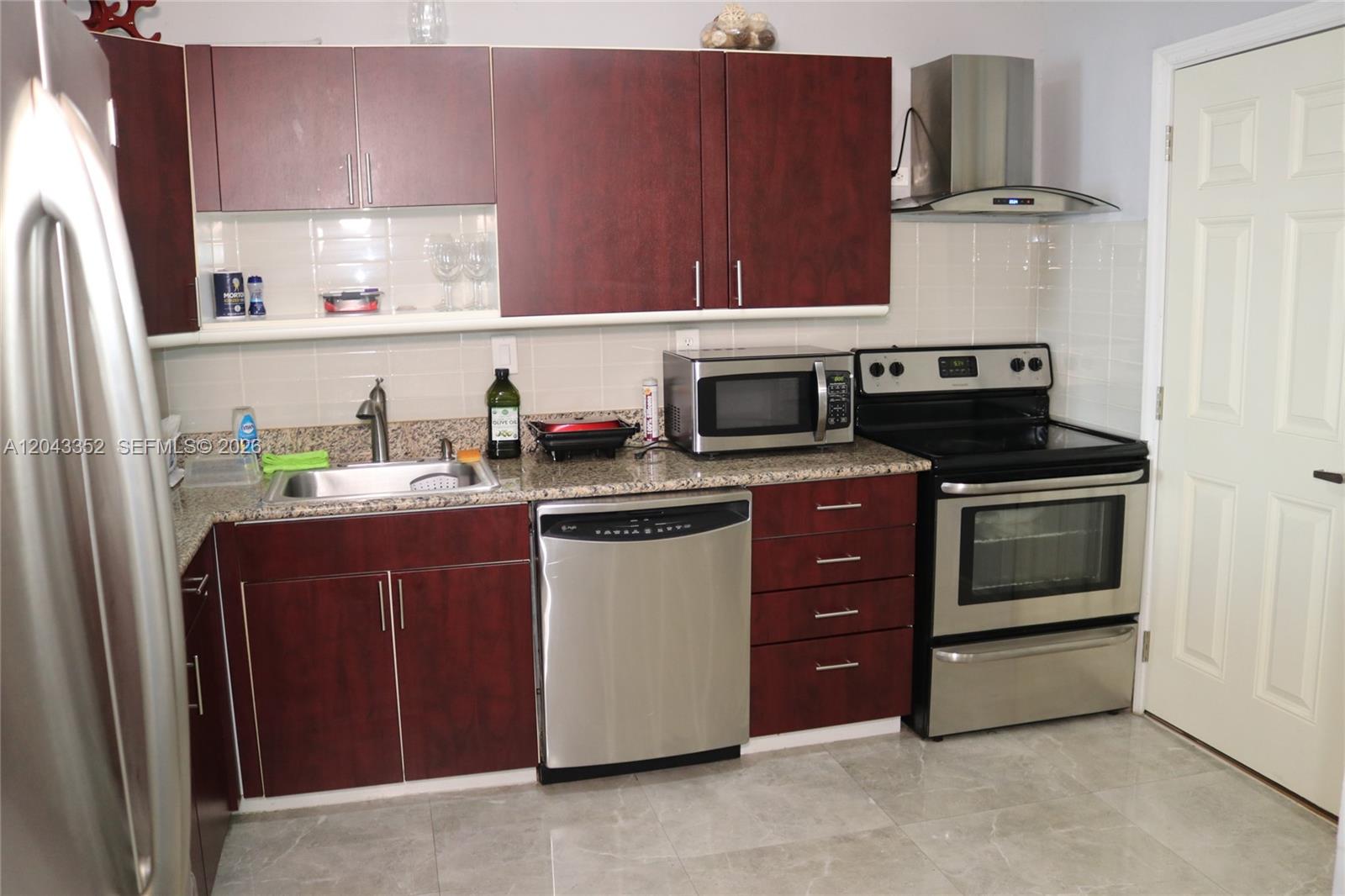 A kitchen features dark wood cabinets, stainless steel appliances, and granite countertops — 1150 NE 191st St # 37, Miami FL 33179, MIAMI, FL